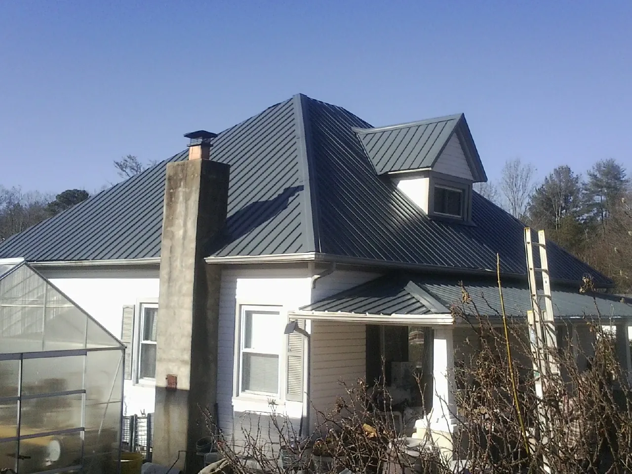 Dark blue standing seam metal roof on a white farmhouse with dormer — Slate & Tile Roof Repair by Roofing Brothers in Adams