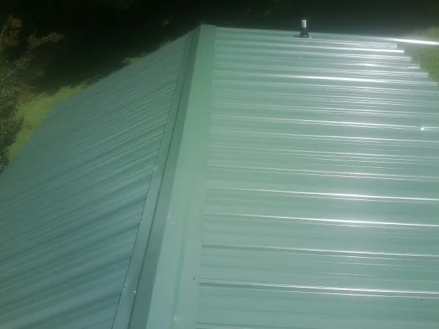 New green metal panels meeting at the ridge of a roof — Flat Roof Repair work by our crew in Adams